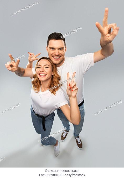 happy couple in white t-shirts showing peace