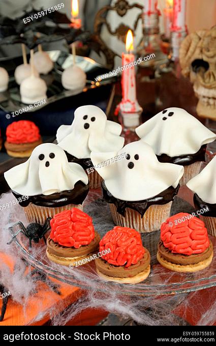 Smorgasbord of biscuit with brains and cupcakes in chocolate glaze decorated marzipan ghosts on Halloween