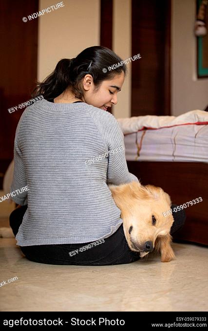 A YOUNG GIRL LOOKING AT PET DOG LYING ON HER LAP