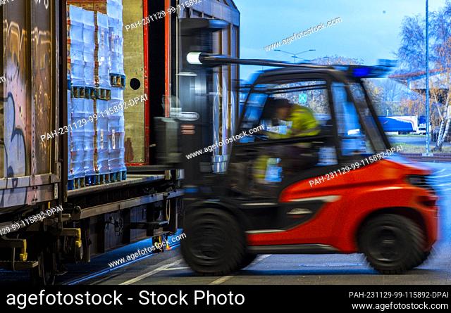 PRODUCTION - 21 November 2023, Mecklenburg-Western Pomerania, Rostock: Pallets and transported goods are reloaded into wagons by trailers of the logistics...