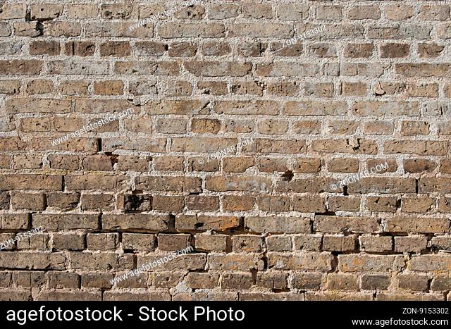 Old brick wall with worn stones and dark colors