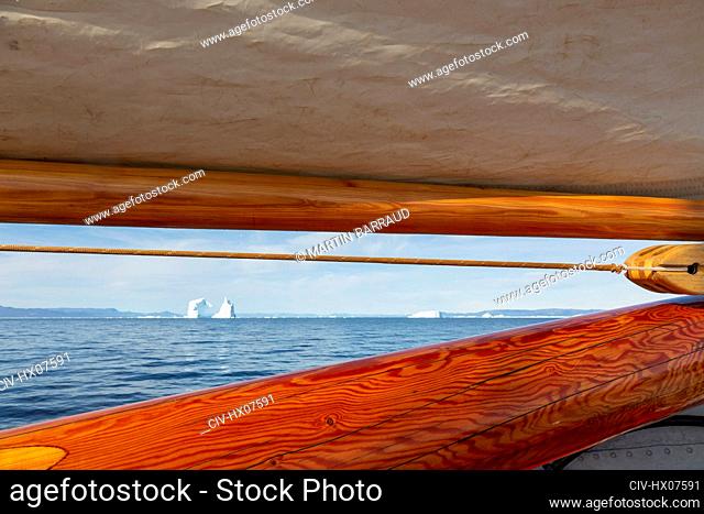 View of icebergs in distance beyond wooden sailboat mast Greenland