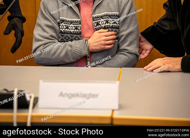 21 December 2023, Baden-Württemberg, Ulm: Handcuffed, a man sits in the dock at the district court. The defendant is accused of spreading petrol along a wall of...