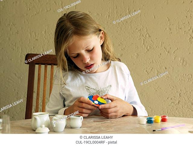 Girl painting china tea set