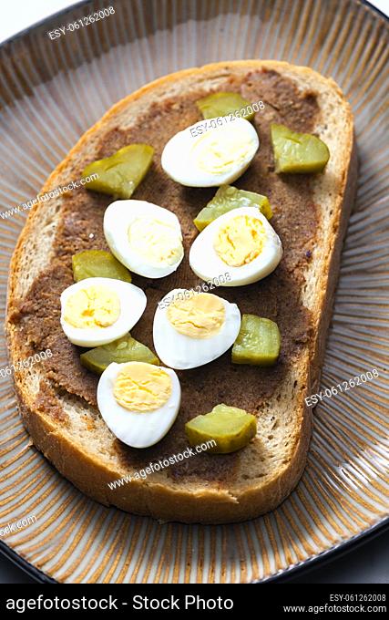 cracklings spread with pickled cucumber and boiled egg on slice of bread