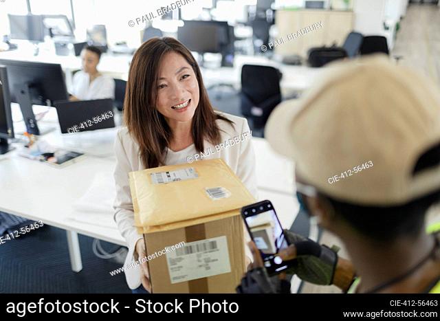 Happy businesswoman receiving packages from courier in office