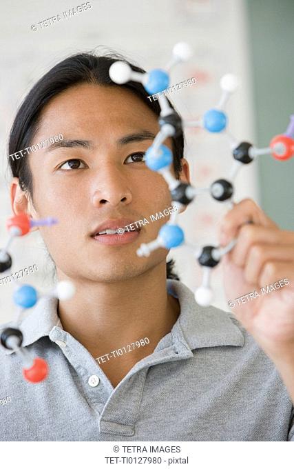 Asian male college student looking at molecule model