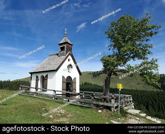 01 September 2023, Austria, Strobl: A woman looks inside the historic Postalm Chapel, which stands at an altitude of 1284 meters on the Postalm in the...