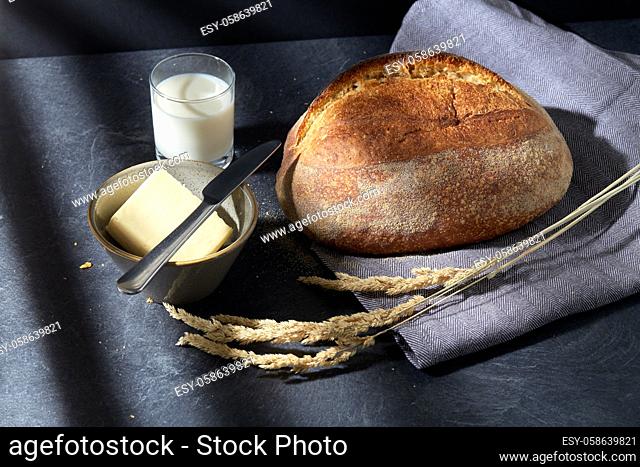 close up of bread, butter, knife and glass of milk