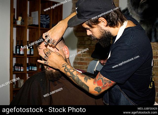 Man in barber shop getting his beard shaved with razor blade
