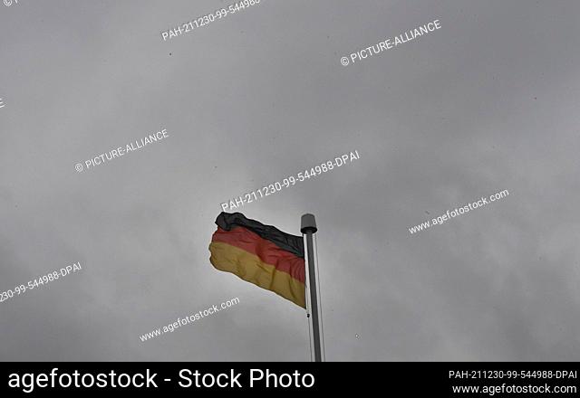 30 December 2021, North Rhine-Westphalia, Königswinter: A German flag flies in the dreary grey sky on the Petersberg. The weather is grey in grey with rain
