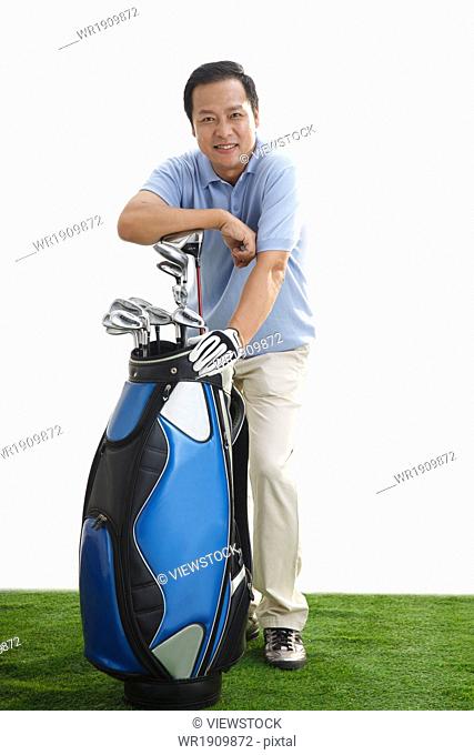 The middle-aged man is leaning on the golf bag