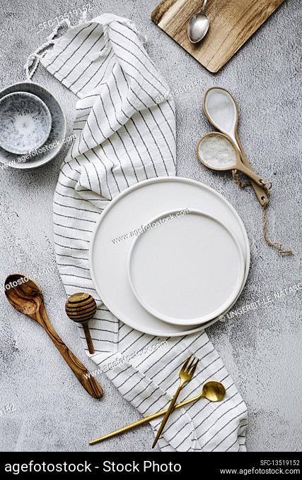 White plates, small bowls, cutlery, and striped linen napkin
