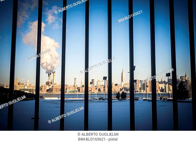 Bars in front of smokestack in city skyline, New York, New York, United States