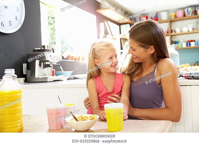 Mother And Daughter Having Breakfast At Kitchen Table