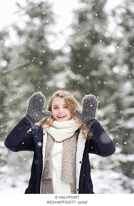 Portrait of happy young woman at snowfall in nature