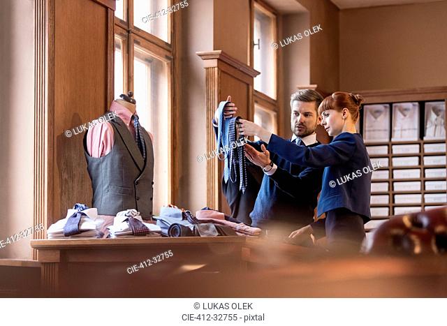 Worker showing ties to businessman in menswear shop