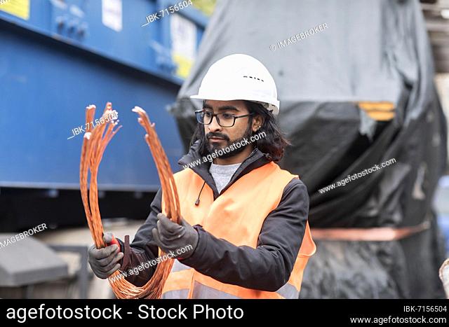 Technician with beard and helmet working in a recycling yard, Freiburg, Baden-Württemberg, Germany, Europe