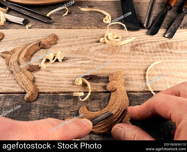 Carved oak decorative elements on a rustic workbench with chisels, wood working or creativity concept with space for text