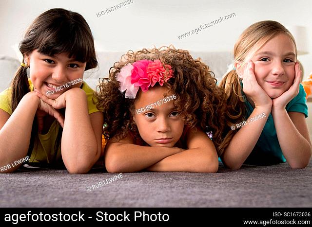 Portrait of three girls lying on front
