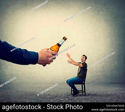 Alcohol addicted man, hands outstretched, receiving a huge bottle of beer from an unknown person hand. Illegal alcohol contraband