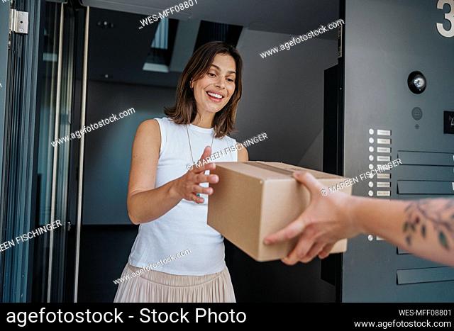 Happy woman receiving packages from delivery person at door