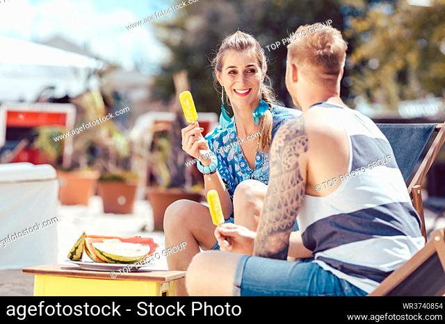 Happy young couple enjoying popsicles at beach
