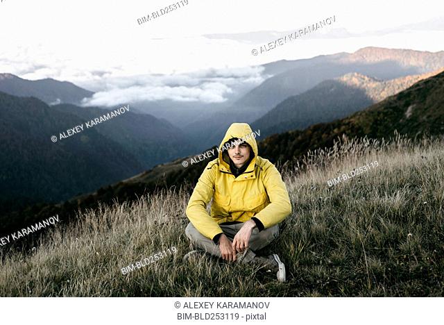 Caucasian man sitting in remote mountain landscape