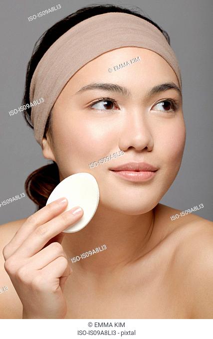 Young woman using make up sponge