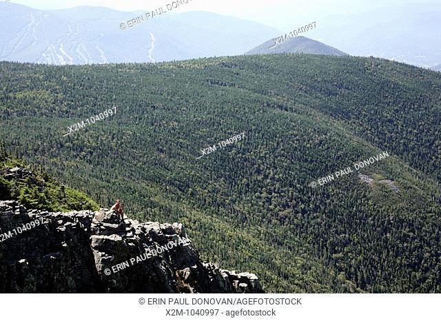A hiker explores and photographs the rocky summit of Mount Flume during the summer months     Located in the White Mountains, New Hampshire USA