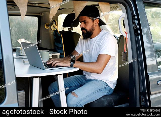 Mature man using laptop while sitting in van