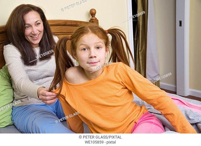 Preteen redhead girl and her mother sitting in bed