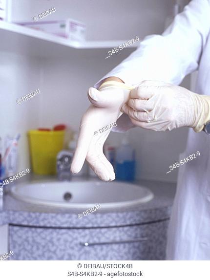 Woman Doctor putting on Rubber-Gloves - Sanitation