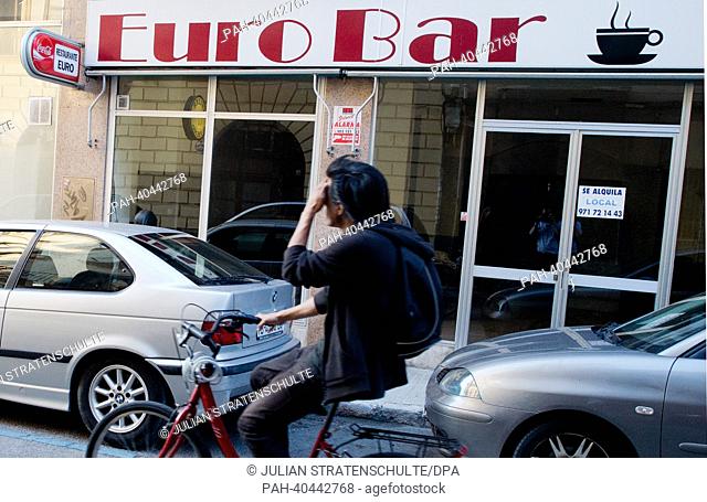 A person cycles past the closed restaurant 'Euro Bar', in which a sign with the lettering 'for rent' (se alquila) is visible in Palma de Mallorca on the...