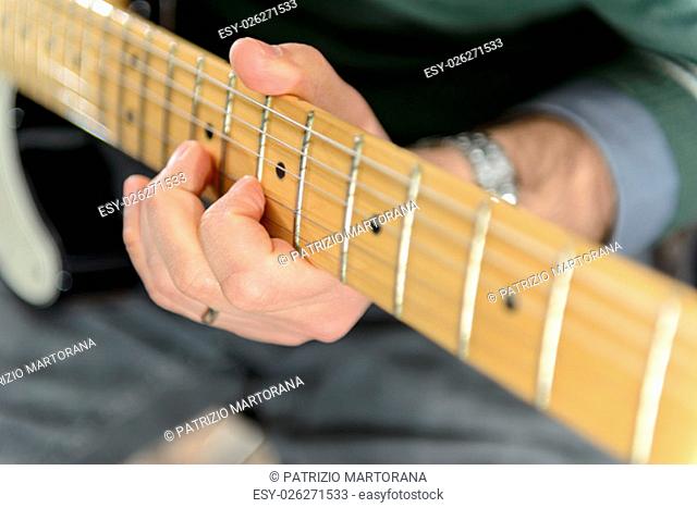 Detail of an electric guitar. Hands moving on the keyboard. Close up. Particularly small and out of focus