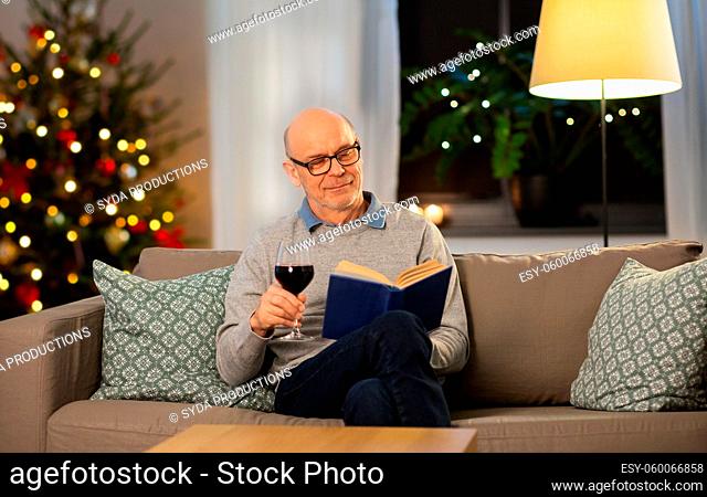 senior man with book drinking wine on christmas