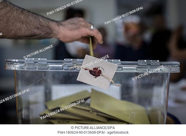 A man casts a ballot in a sealed ballot box at a polling station in Istanbul, Turkey, 24 June 2018. The country is holding snap twin elections