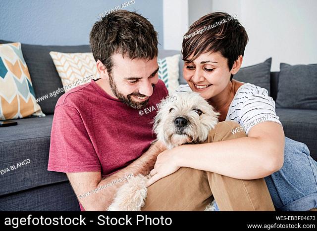 Man and woman playing with dog at home