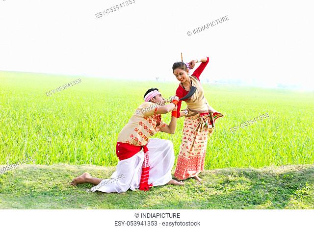 Bihu man blowing on a pepa while Bihu woman dances to his tune