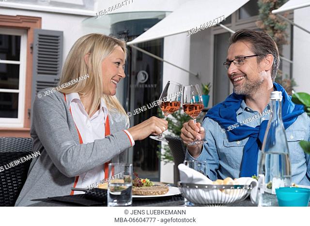 Man and woman while eating, chink with rose wine