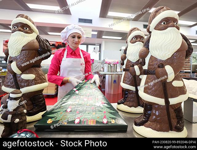 17 August 2023, Thuringia, Schmalkalden: Employee Josephiene Erbe stands between four-kilogram Santa Clauses and Advent calendars in Viba's production facility