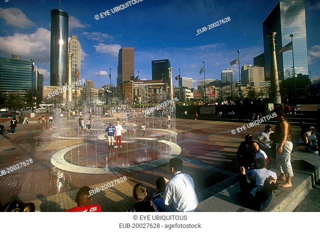 Centennial Olympic Park. Visitors around paved area with fountains, city skyline behind