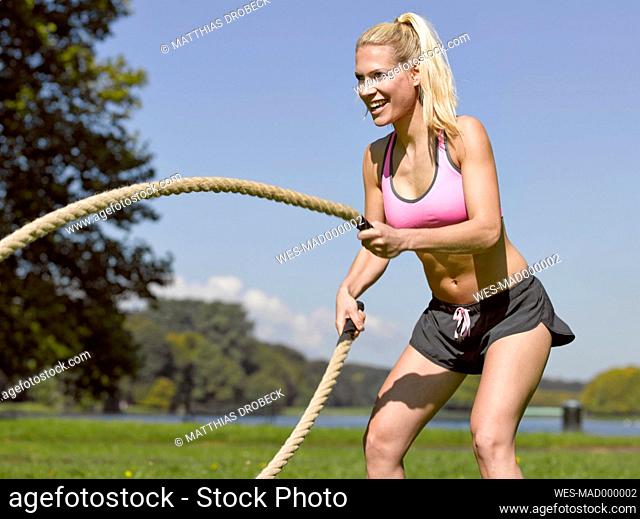 Germany, Young woman doing sports with ropes