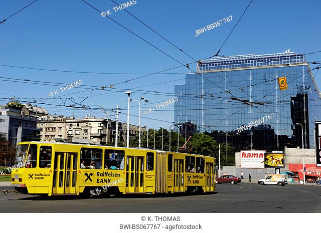 Beograd, modern yellow street car with a logo of Raiffeisen bank, modern office building in the background, Serbia-Montenegro, Belgrade