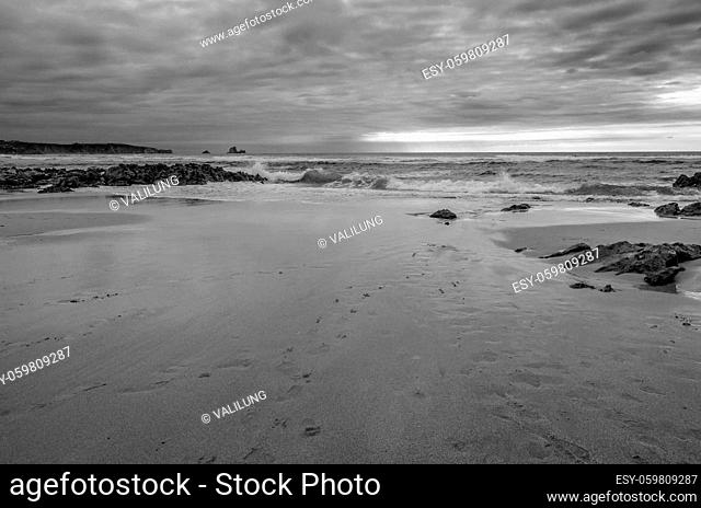 View of Valdearenas beach in Cantabria, Spain, at sunset. Black and white image