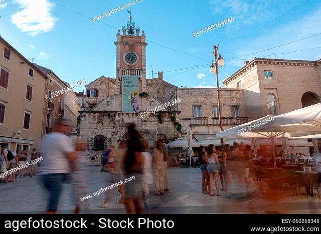 Zadar, Croatia - July 8 2018: Zadar main square with blurred tourist rushing for sightseeing in late afternoon, street caffees in background with people having...