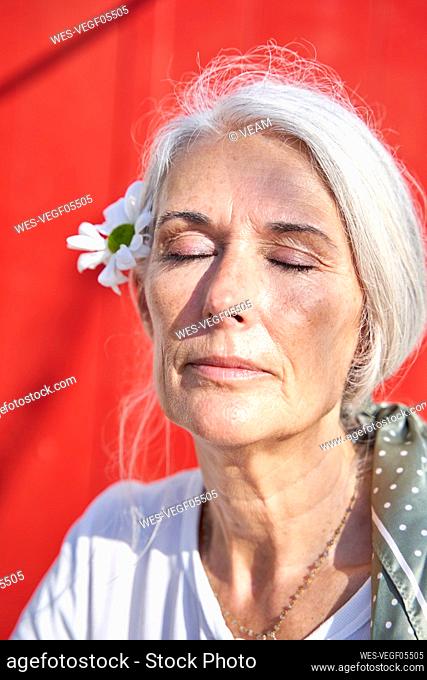 Woman with eyes closed wearing flower on sunny day