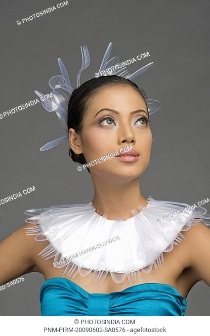 Female fashion model with neck ruff and headwear of plastic forks and spoons