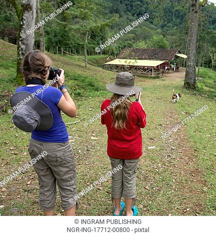 Two girls taking picture with digital cameras in a farm, Finca El Cisne, Honduras