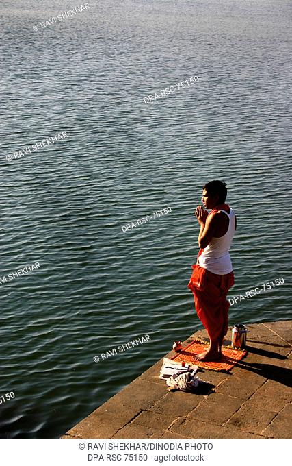 Man worshiping  with folded hands , on bank of Narmada river , Maheshwar ,  Madhya Pradesh , India